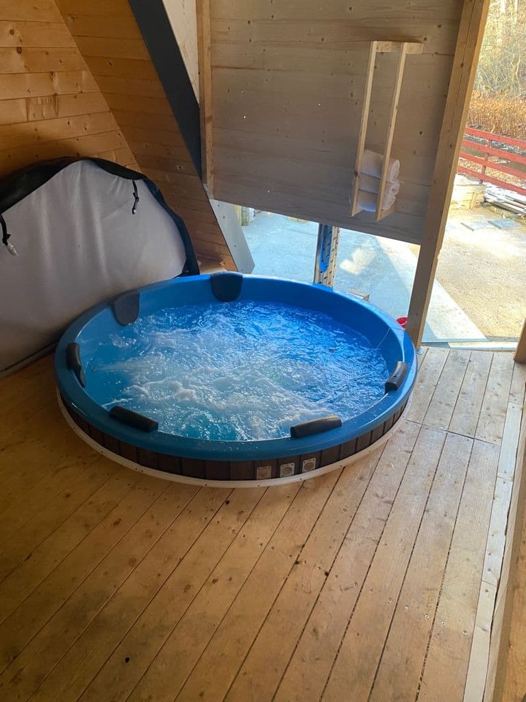 Jacuzzi cu hidromasaj pornit, văzut de sub pavilion, cu deschiderea spre curte.