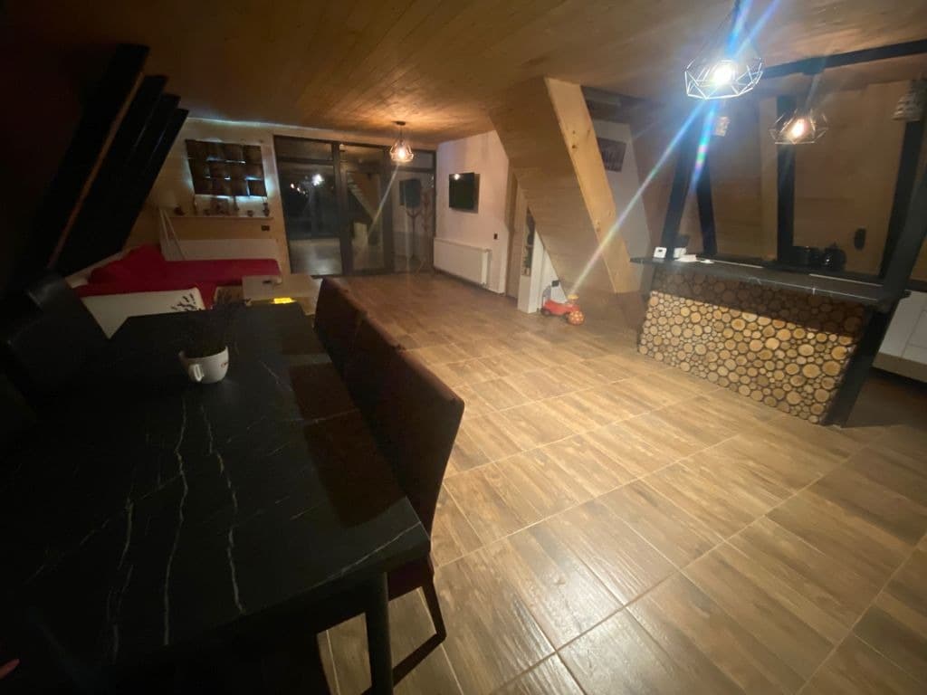 Masa de dining și barul din bucătărie, seara, cu lumina interioară aprinsă.
